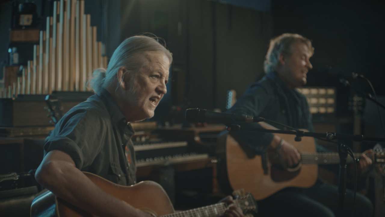 two men singing and playing guitar